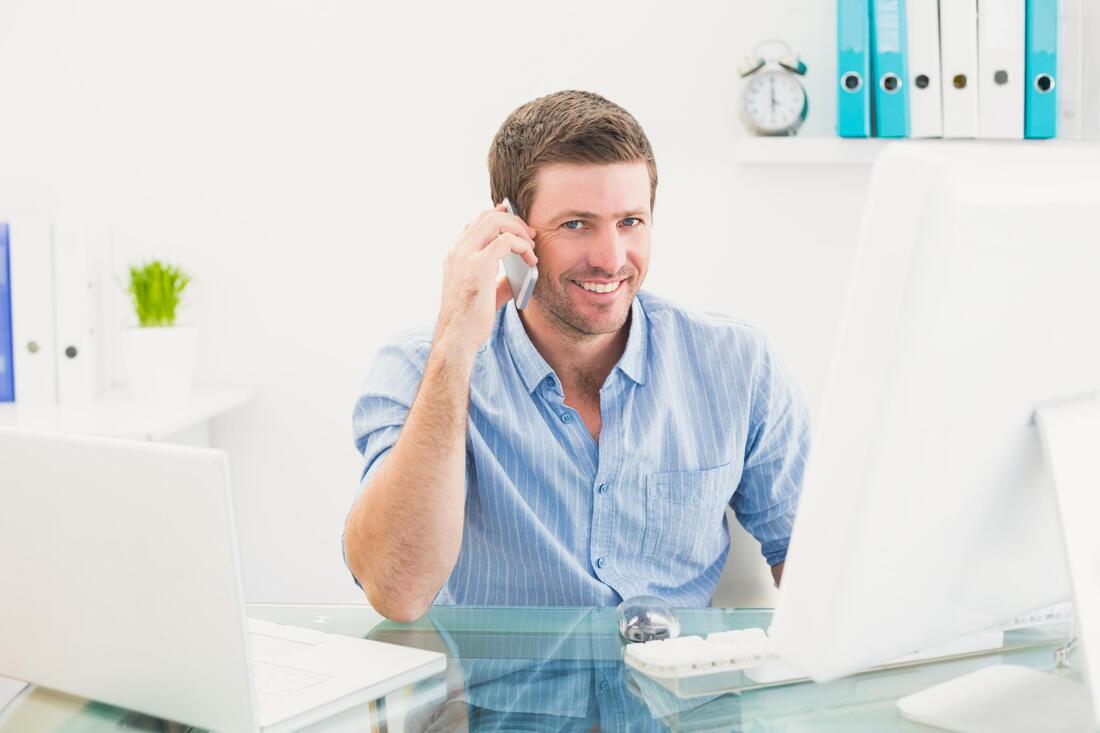 man calling on his phone, utilizing office staff and support.